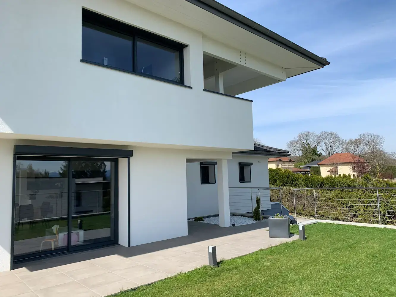 Terrasse extension rez-de-chaussée — grande baie vitrée, surélévation en fond, relation intérieur-extérieur — Divonne-les-Bains