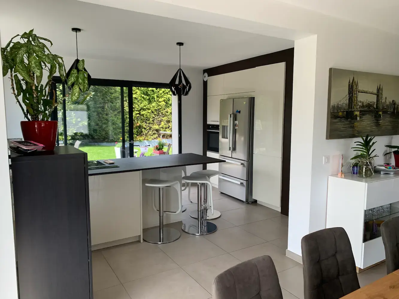 Cuisine ouverte après réhabilitation totale — îlot central, tabourets design, baie vitrée sur jardin — Divonne-les-Bains