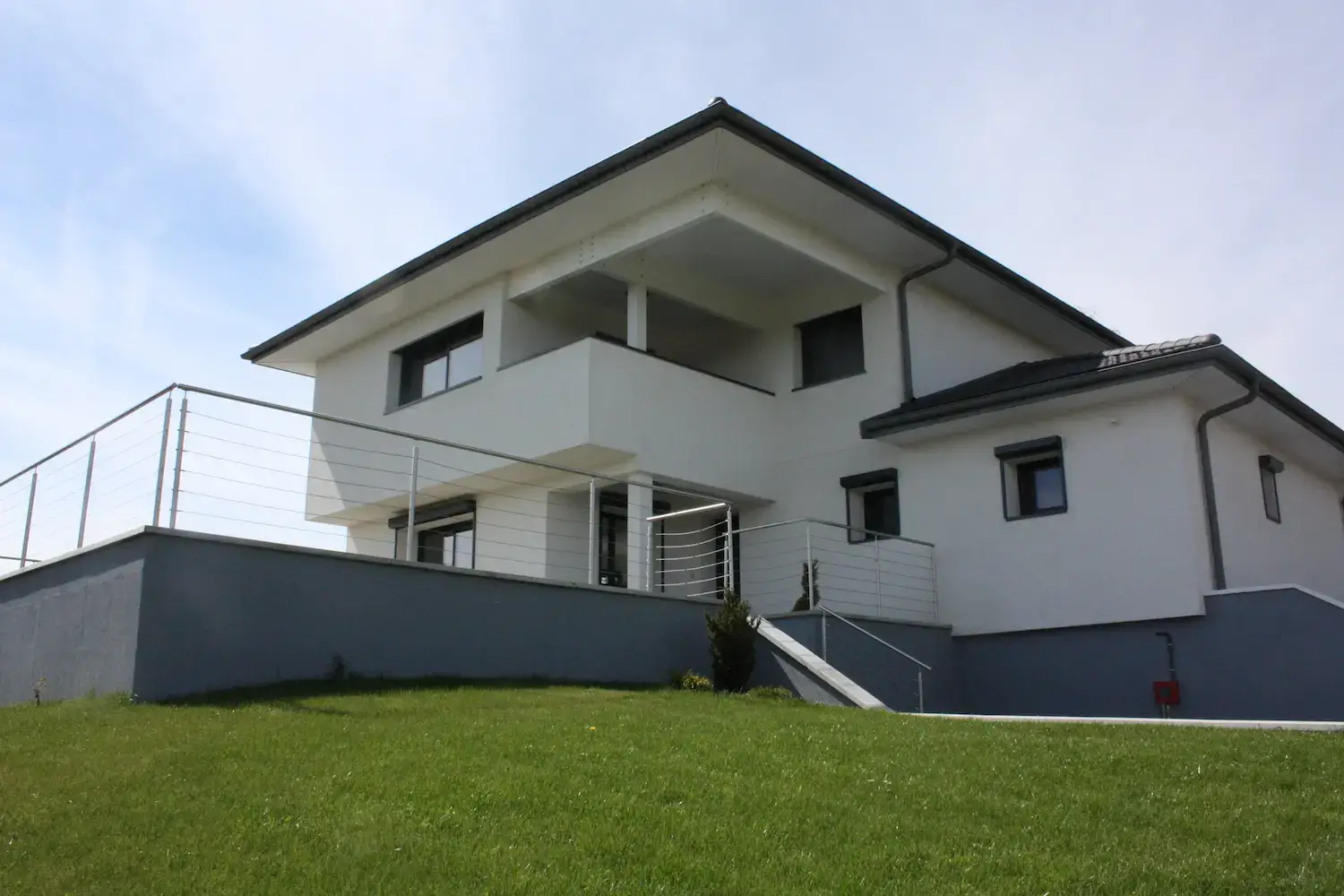 Extension et surélévation d'une maison individuelle à Divonne-les-Bains — vue jardin, façade réhabilitée — architecte Pays de Gex
